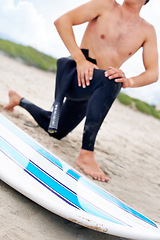 Image showing Surfer, man stretching legs and surfboard on beach, fitness and extreme sport, ready for waves with travel and sand. Summer, wet suit and warm up, start surfing and nature with adventure outdoor