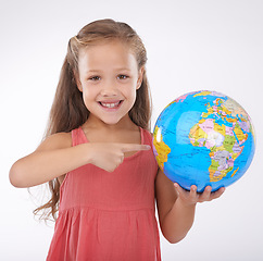 Image showing Kid, pointing to globe in studio with world, planets and city for education, geography and portrait. Student, girl child and travel map with smile for earth day support or ecology on white background