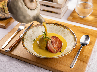 Image showing Waiter pours cream soup into a baked potato