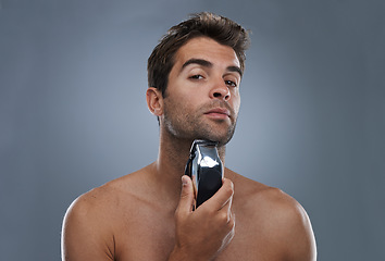 Image showing Man, shaving and electric razor in studio portrait for grooming, skincare and wellness by grey background. Person, model and beard with hygiene, facial hair removal and product for cosmetic change