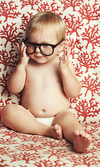 Image showing Smile, glasses and fun baby in studio with vision, eye care and health for child development. Happy, cute and young infant, toddler or kid playing with spectacles or eyewear by wallpaper background.