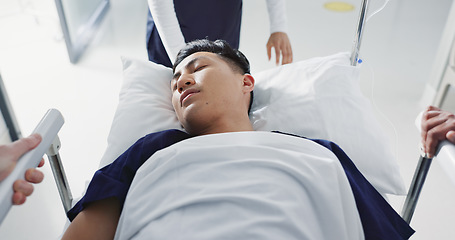 Image showing Emergency, bed and man in hospital for medical surgery with team of doctors in clinic corridor for healthcare. Sick, group and person in first aid bed for accident health service or assessment