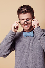 Image showing Portrait, smile and glasses for fashion with a man in studio on a tan background for vision or style. Style, eyewear and a confident young geek or nerd with prescription frame lenses for eyesight