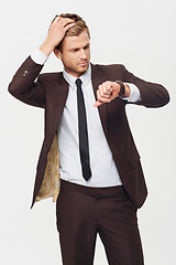 Image showing Businessman, watch and checking time in late, stress or schedule deadline against a white studio background. Attractive young man looking at wristwatch in suit for mistake, business or fashion style