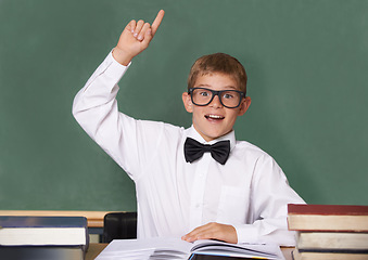 Image showing Boy child, books and raised hand in portrait with smile for question, information and knowledge on classroom. Student kid, happy and excited for education, learning and development by chalkboard