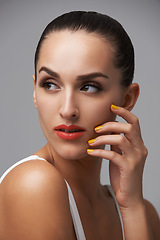 Image showing Woman, face and manicure with lipstick for beauty, yellow nail polish and cosmetics on grey background. Cosmetology, orange lips and hand with color nails, confident in makeup and glamour in studio