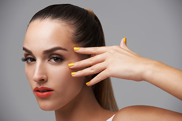 Image showing Woman face, beauty and hand with manicure, makeup and yellow nail polish, skin and cosmetics on grey background. Orange lipstick, color nails and model in portrait, confidence in studio and glamour