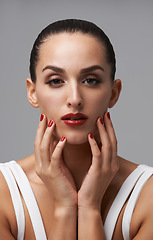 Image showing Woman, portrait and red lipstick with beauty and manicure, nail polish and cosmetic care for skin on grey background. Face, confidence and bold makeup with hands and color nails for glamour in studio