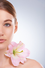 Image showing Half face, woman and dermatology with flowers, beauty and wellness on white studio background. Closeup, portrait or model with natural cosmetics or grooming with shine or glow with skincare or smooth