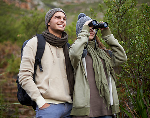 Image showing Couple, travel and binoculars in nature for hiking, adventure and journey or explore together in winter. Happy man and woman trekking with outdoor search, vision or birdwatching in forest or woods