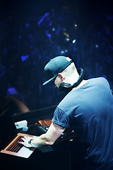 Image showing Concert, DJ and man with mixing music by stage and laptop in color spotlight with large crowd. Young person, creative and talented musician in band for sound and performance at event on night club