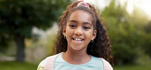 Image showing Child, face and girl smile outdoor in a garden, park or green environment for fun and happiness. Portrait of a young african female kid with a positive mindset, cute hairstyle and nature to relax