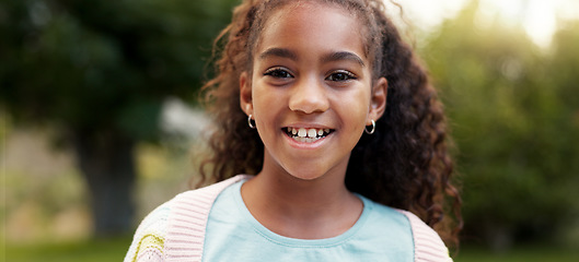 Image showing Face, child or girl laughing outdoor in a garden, park or green environment for fun and happiness. Portrait of a young African female kid with a positive mindset, cute smile and nature to relax