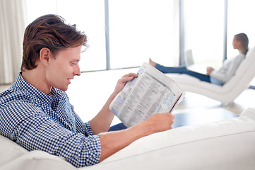 Image showing Man, newspaper and reading on sofa with relax for story, article or information with smile in living room. Person, news and morning routine on couch with print media or knowledge for break in lounge