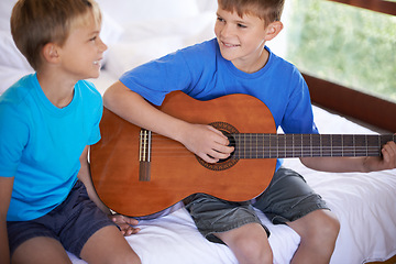 Image showing Children, music and siblings on a bed with guitar for playing, bonding or learning together in their home. Musical instrument, love and kids in bedroom with acoustic sound, teaching or having fun