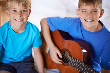 Image showing Smile, portrait and children with guitar on bed for playing or practicing music together at home. Happy, bonding and young boy kids learning an acoustic string instrument in bedroom at house.