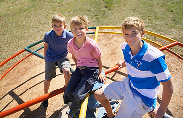 Image showing Friends, brothers and playing at park in portrait, kids and smile on merry go round at playground. Happy siblings, carousel and bonding on outdoor adventure, boys and active on vacation or holiday