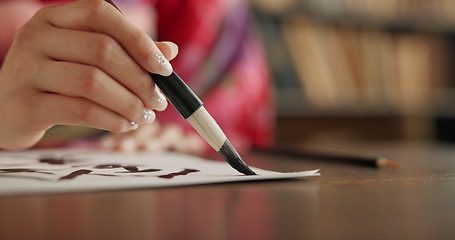 Image showing Ink, Japanese writing and person in traditional home for script, documents and paper on desk. Creative, Asian culture and hands with vintage paintbrush tools for calligraphy, font and text in house