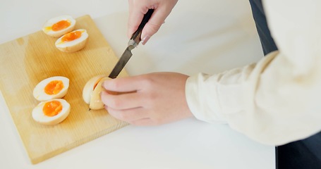 Image showing Chef hands, knife and boiled eggs in kitchen for cooking, protein or prepare food for catering service. Person, chopping board and ready for cuisine, fine dining or nutrition on table in restaurant