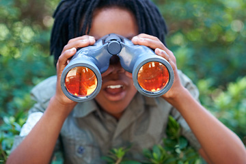 Image showing Boy, kid with binoculars and surprise, search in nature for learning and fun, forest and adventure at summer camp. Young African camper, leaves and explore environment outdoor with wow for discovery