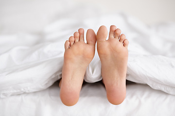 Image showing Bed, feet and person sleeping in home, relax and resting nap in sheets for health, calm and leisure in the morning. Foot, bedroom and closeup of toes in blankets, skin of legs and comfort in house