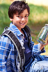 Image showing Boy, child and smile with jar in nature, exploring and learning on adventure, hiking in park or woods for fun. Portrait, happy and young explorer, discovery and glass container for collecting bugs