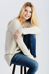 Image showing Fashion, smile and chair with portrait of woman in studio on white background for casual style. Relax, aesthetic and happy or confident young blonde model sitting on wooden stool in clothing outfit