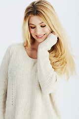 Image showing Fashion, smile and blonde with woman shy in studio on white background for casual winter style. Model, happy and wool sweater with young girl in relaxed outfit of pullover jersey for warm comfort