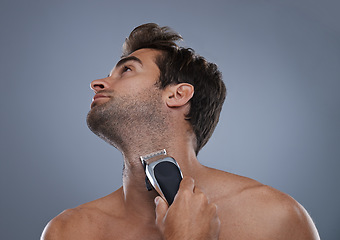 Image showing Man, electric shaver and beard in studio for grooming, skincare or wellness for neck by grey background. Person, model and self care for hygiene, facial hair removal or clippers for cosmetic change