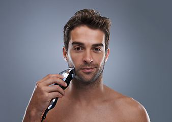 Image showing Man, electric shaver and studio portrait for grooming, skincare and happy for wellness by grey background. Person, model and beard with hygiene, facial hair removal and product for cosmetic change