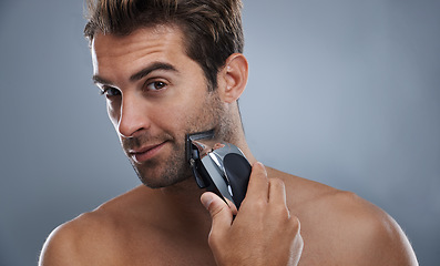 Image showing Man, beard and electric razor in studio portrait for grooming, skincare and wellness by grey background. Person, model and shaving with hygiene, facial hair removal and product for cosmetic change