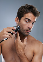 Image showing Man, grooming and electric razor in studio portrait for beard, skincare and wellness by grey background. Person, model and shaving with hygiene, facial hair removal and product for cosmetic change