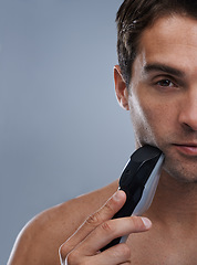 Image showing Man, electric shaver and face with closeup studio portrait, grooming and skincare by grey background. Person, model and shaving beard with hygiene, facial hair removal or mockup for cosmetic change