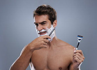 Image showing Man, choice and razor in studio, shaving cream or portrait for grooming by grey background. Person, model and decision for blade with beard, facial hair removal and doubt product for cosmetic change