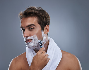 Image showing Man, razor and shaving cream in studio portrait for grooming, skincare and wellness by grey background. Person, model and beard with hygiene, facial hair removal and foam product for cosmetic change