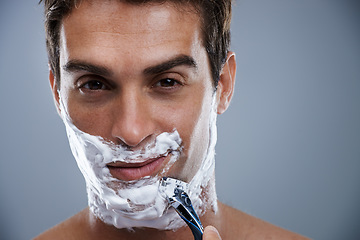 Image showing Man, razor and shaving in studio closeup for grooming, skincare and beard in portrait by grey background. Person, model and self care with cream, facial hair removal and product for cosmetic change