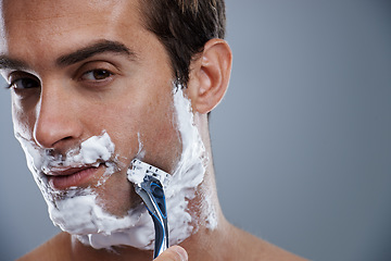 Image showing Man, blade and shaving in studio portrait for wellness, skin or grooming with cream by grey background. Person, model and closeup with beard, facial hair removal and foam product for cosmetic change