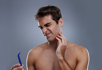 Image showing Man, shaving and beard or razor burn in studio for hair removal mistake, inflammation or grey background. Male person, tool and leaning or unhappy accident for wellness maintenance, pain or mockup