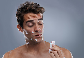 Image showing Man, face and shave cuts or paper for hair removal hygiene or injury with blood, tissue or maintenance. Male person, grey background and dermatology with beard or clean health, studio or mockup space