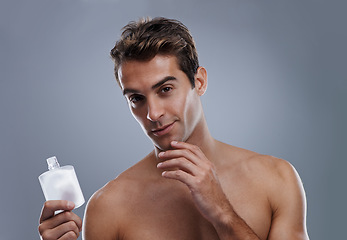 Image showing Studio, portrait and man with aftershave for skincare, grooming and facial treatment or cologne. Model, face and happy with bottle for cosmetics product, fragrance and male beauty by gray background