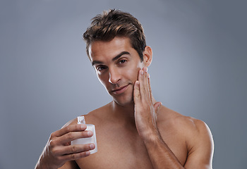 Image showing Portrait, cream and man with skincare, wellness and beauty with lotion and moisture with glow and bottle on a grey studio background. Portrait, person and model with grooming routine and treatment