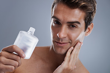 Image showing Studio, portrait and man with aftershave for beauty, grooming and facial treatment or cologne. Model, face and happy with bottle for cosmetics product, fragrance and male skincare by gray background