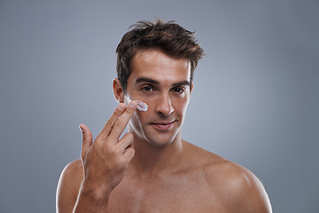 Image showing Portrait, cream and man with skincare, shine and beauty with glow on grey studio background. Apply, person and model with morning routine or treatment with lotion or moisture with wellness or face