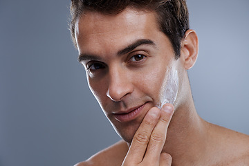 Image showing Portrait, cream and man with skincare, glow and moisture on a grey studio background. Face, person and model with grooming routine and treatment with lotion and dermatology with wellness or shine