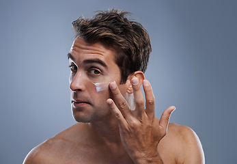 Image showing Portrait, cream and man with skincare, cosmetics and beauty on a grey studio background. Portrait, person and model with grooming routine and treatment with lotion and moisture with wellness and glow