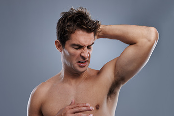 Image showing Armpit, stink and man with body odor, poor hygiene and routine on grey studio background for deodorant, cleaning and skincare. Underarm, bad smell and model with hyperhidrosis, sweating or cosmetics