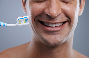Image showing Closeup, toothbrush and man with a smile, clean and wellness on grey studio background. Happy, person and model with dental hygiene or oral health with fresh breath or toothpaste with morning routine
