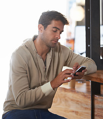 Image showing Phone, networking and young man in a cafe on social media, mobile app or the internet at table. Technology, reading and male person scroll on website with cellphone in restaurant or coffee shop.