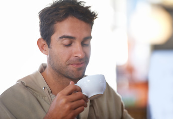 Image showing Smile, coffee and young man in a cafe with positive, good and confident attitude in morning. Happy, cappuccino and male person drinking caffeine, espresso or latte beverage in mug at restaurant.