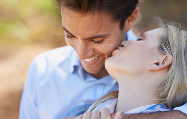 Image showing Happy couple, kiss and hug in nature for embrace, love or support in outdoor walk or bonding. Young woman and man with smile on cheek for affection, comfort or romance in forest or woods together